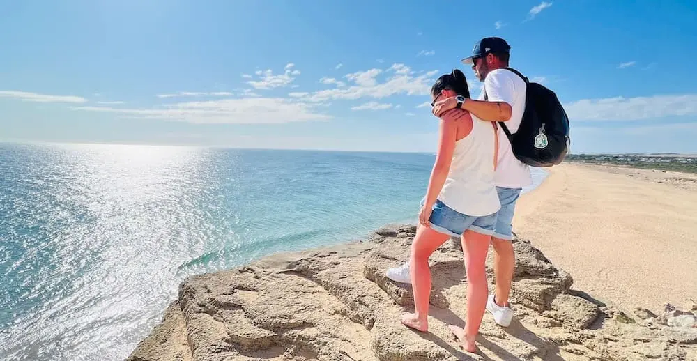 Mujer en crisis acompañada de un amigo contemplando el horizonte y desde la playa